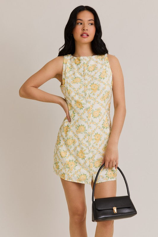 Woman in floral dress holding black handbag.