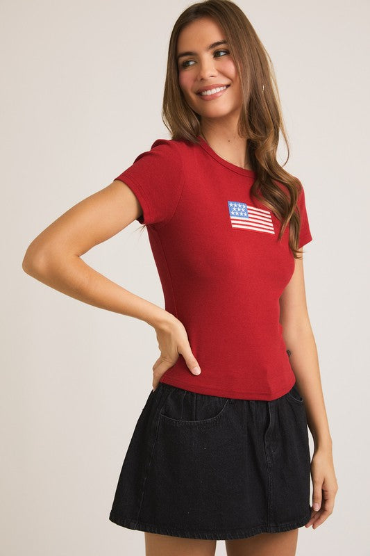 Woman in red shirt with American flag and black skirt.