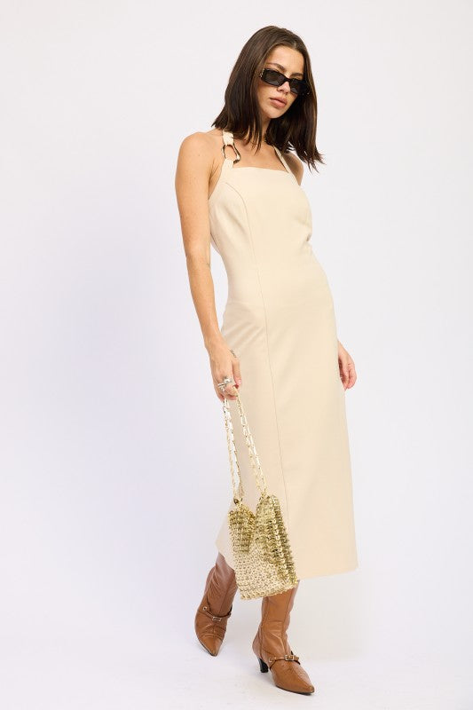 Woman wearing a beige slip dress with a sequin bag on a white background