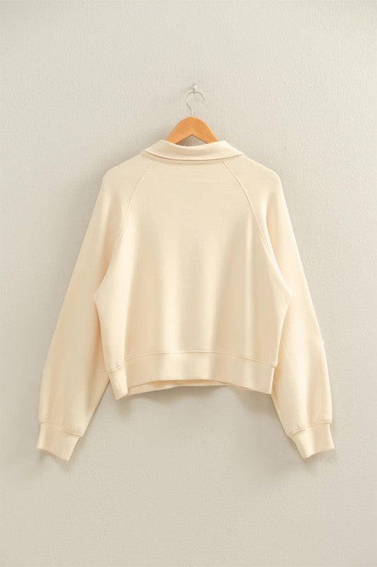 Beige sweatshirt on a wooden hanger against a light gray background
