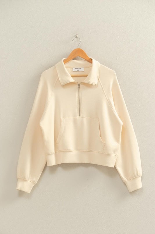 Beige sweatshirt on a wooden hanger against a plain background