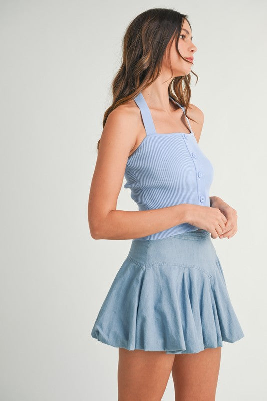 Woman wearing a blue halter top and denim skirt.