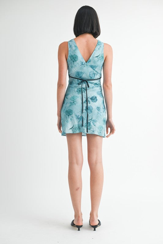 Woman wearing a teal floral dress on a white background