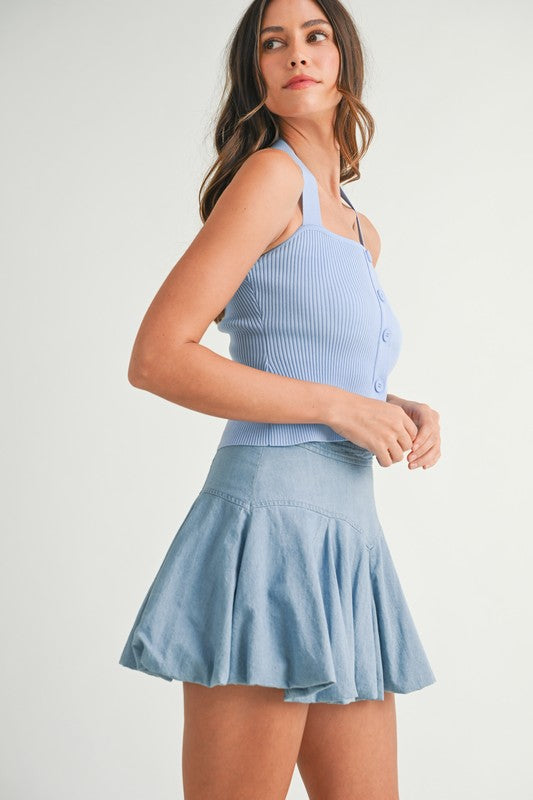 Woman in blue top and denim skirt.