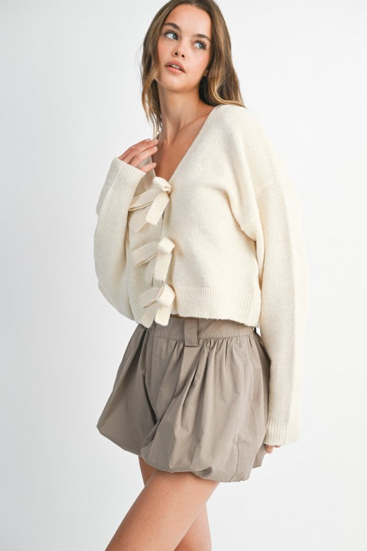 Woman wearing a cream sweater and beige shorts on a white background