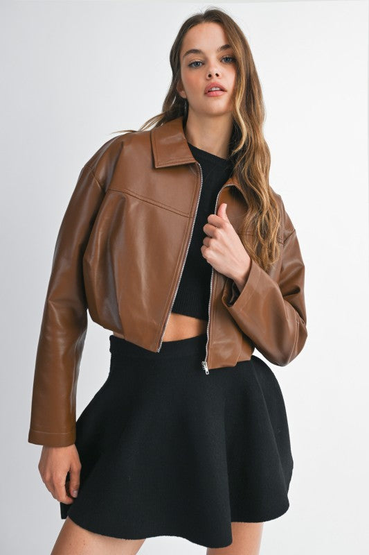 Woman wearing a brown leather jacket and black skirt on a white background