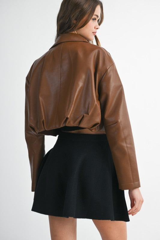 Woman wearing a brown leather jacket and black skirt on a white background