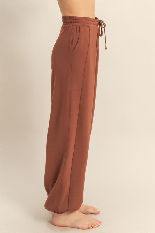 Brown wide-leg pants with drawstring waist on a beige background