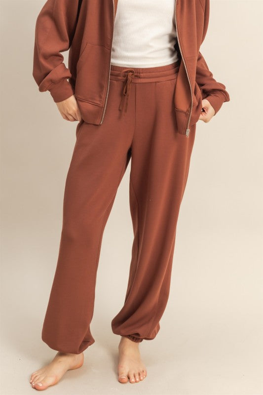 Brown tracksuit worn by a person on a plain background