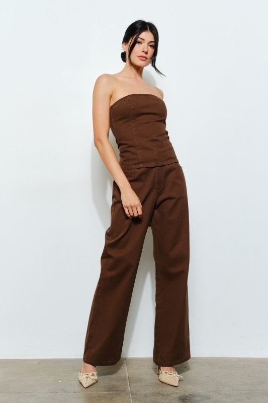 Woman wearing a brown strapless jumpsuit against a white background