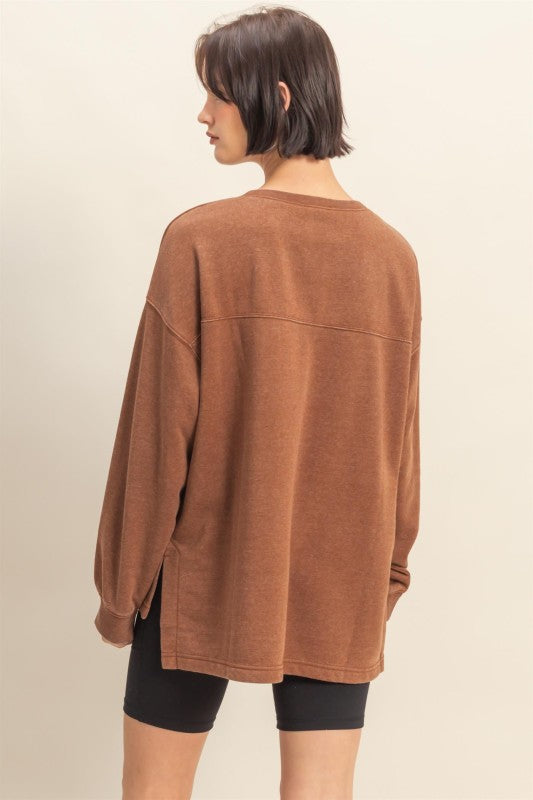 Person wearing a brown oversized sweater on a beige background