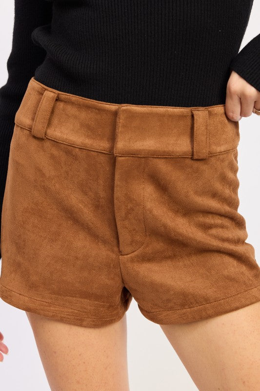 Brown shorts worn by a person on a white background