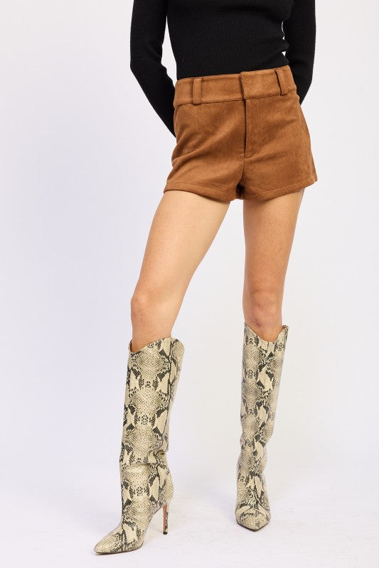 Person wearing brown shorts and snake print boots on a white background