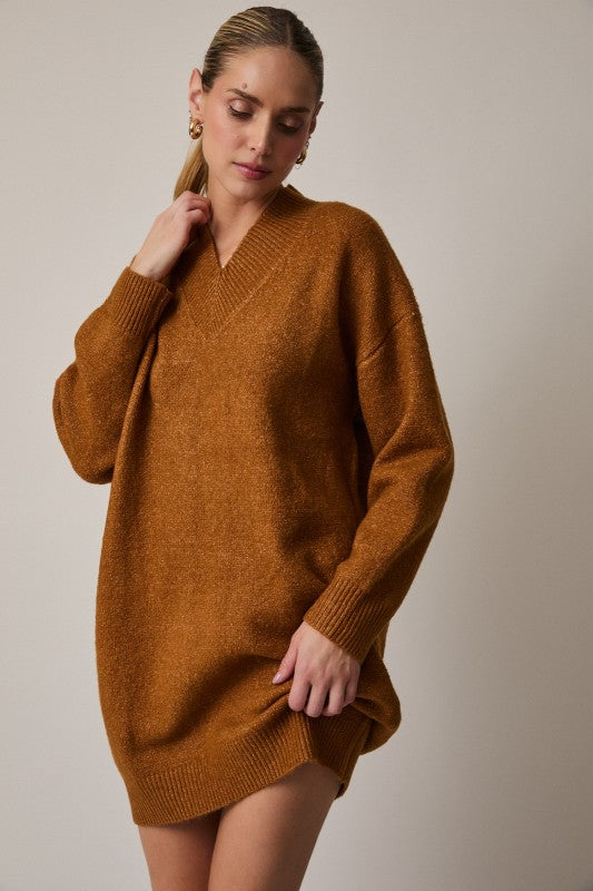 Woman wearing a brown sweater dress against a plain background