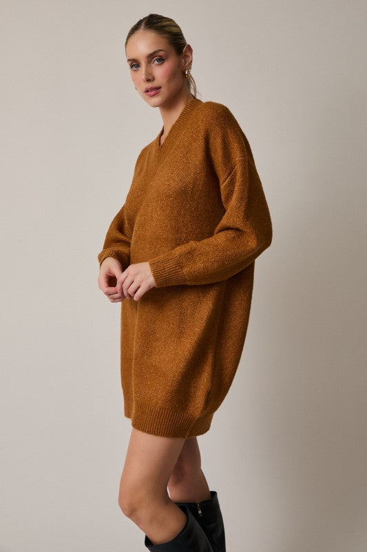 Woman wearing a brown sweater dress against a plain background
