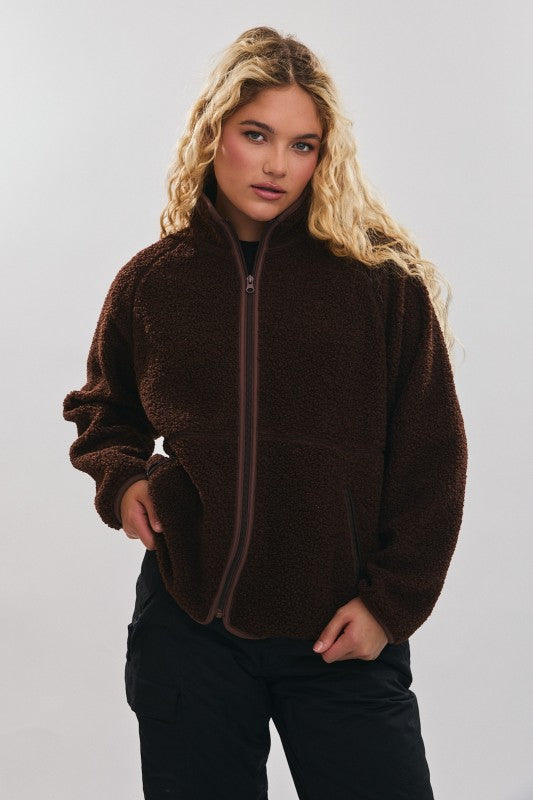 Person wearing a brown fleece jacket on a plain background