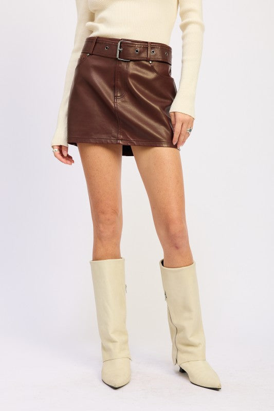 Person wearing a brown leather skirt and beige knee-high boots on a white background