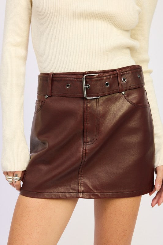 Brown leather skirt worn with a beige sweater on a white background