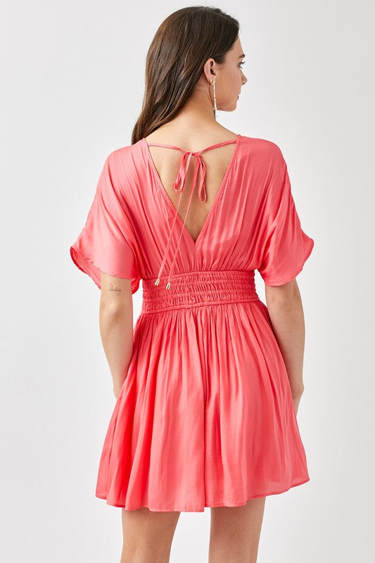 Coral dress with open back worn by a model on a white background