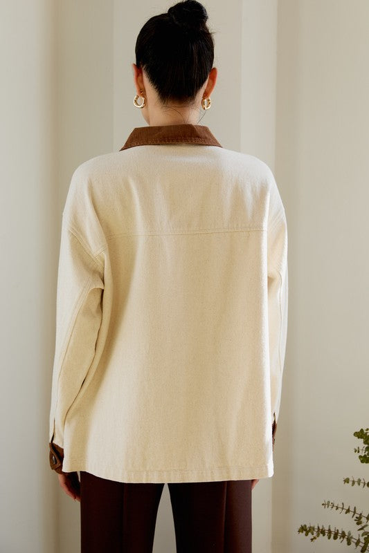 Person wearing a beige jacket with a plain background