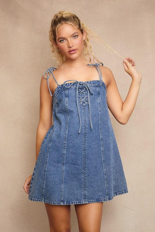 Woman wearing a denim dress against a beige background