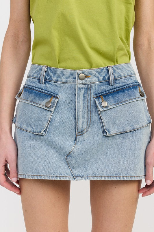 Denim skirt worn with a green top on a plain background