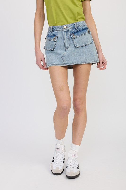 Person wearing a light blue denim skirt with a plain background