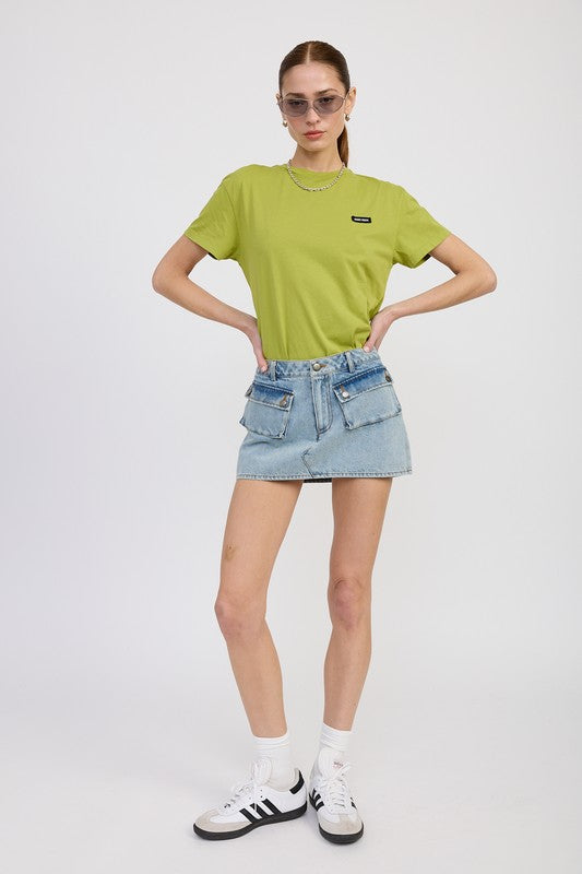 Person wearing a green t-shirt and denim skirt on a white background