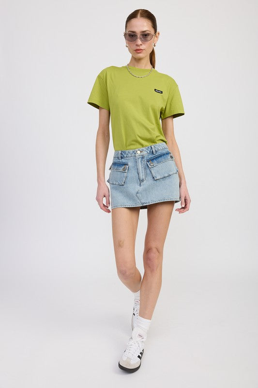 Person wearing a green t-shirt and denim skirt on a white background