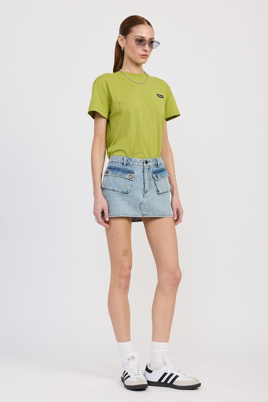 Person wearing a green t-shirt and denim skirt on a white background