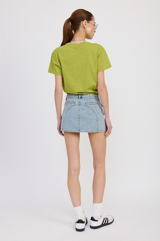 Person wearing a green t-shirt and denim skirt on a white background