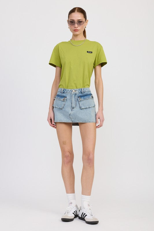 Person wearing a green t-shirt and denim skirt on a white background