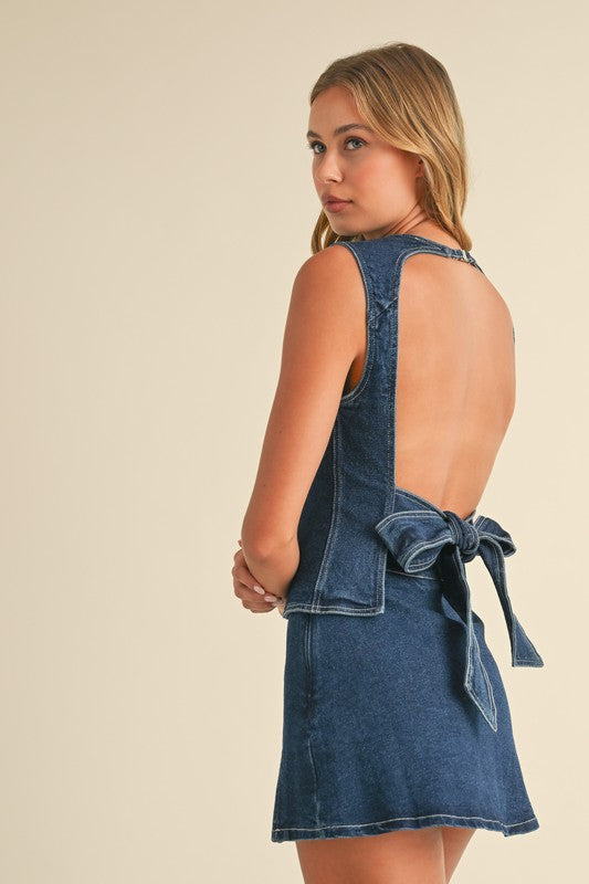 Woman wearing a denim dress with a bow detail on a beige background