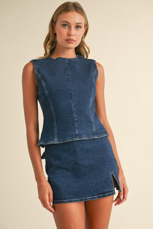 Woman wearing a blue denim dress against a beige background