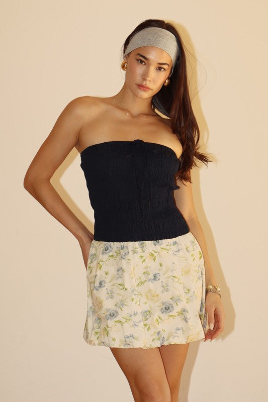 Woman in tube top and floral skirt.