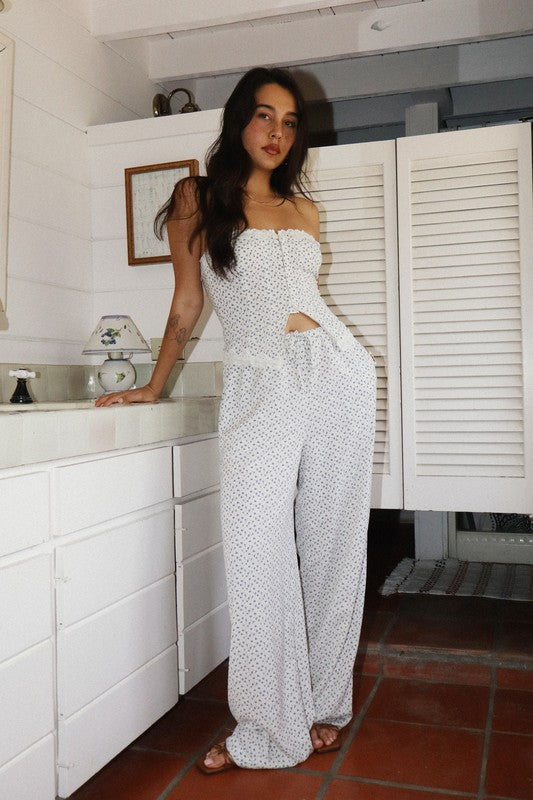 Woman in a white strapless top and pants standing in a kitchen.