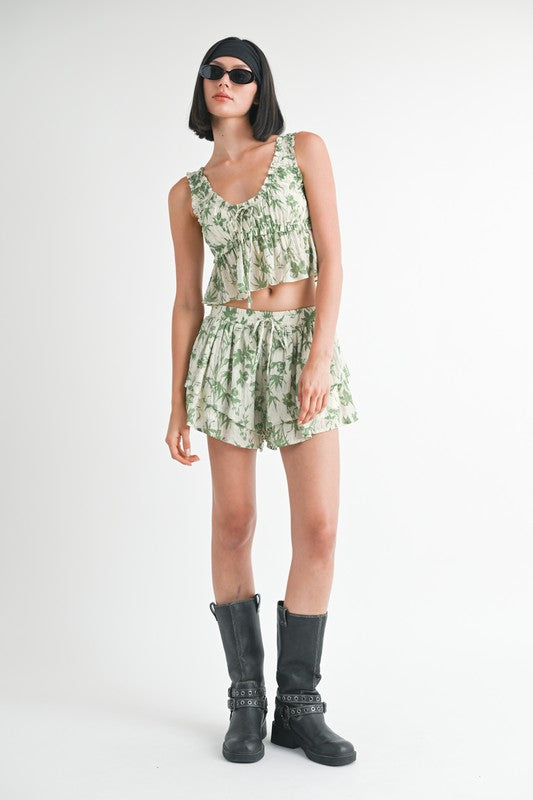Woman wearing a green floral outfit with black boots on a white background
