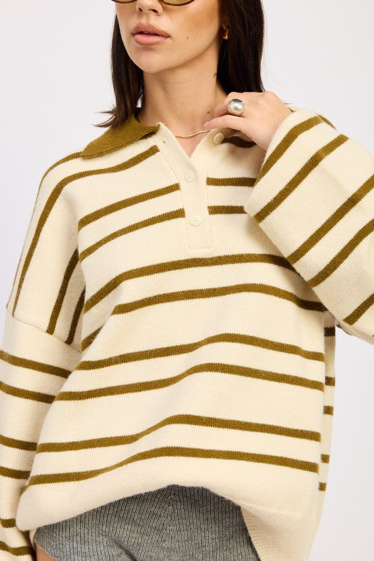 Woman wearing a cream and brown striped sweater on a plain background