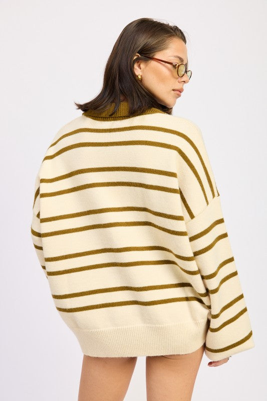 Woman wearing a cream and brown striped sweater on a white background
