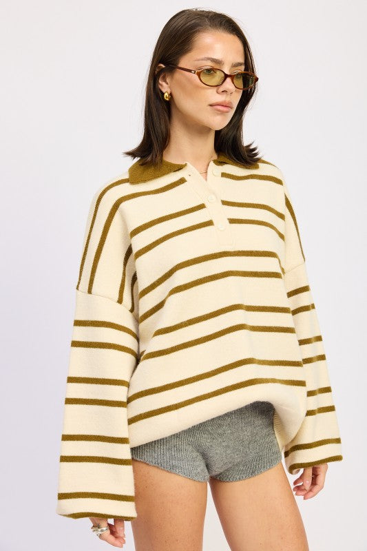 Woman wearing a cream and brown striped sweater with gray shorts on a white background