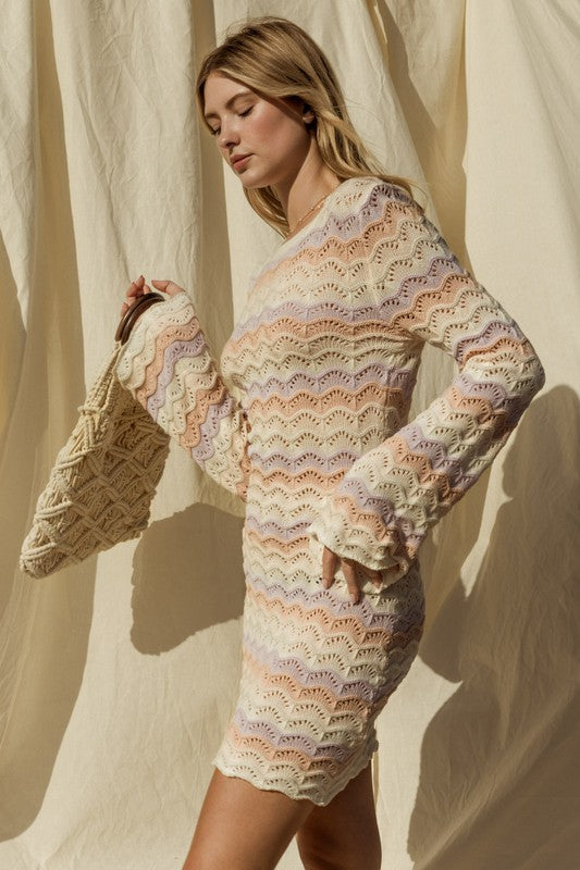 Woman wearing a colorful crochet dress against a neutral background