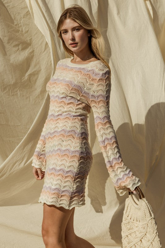 Woman wearing a colorful crochet dress against a neutral background
