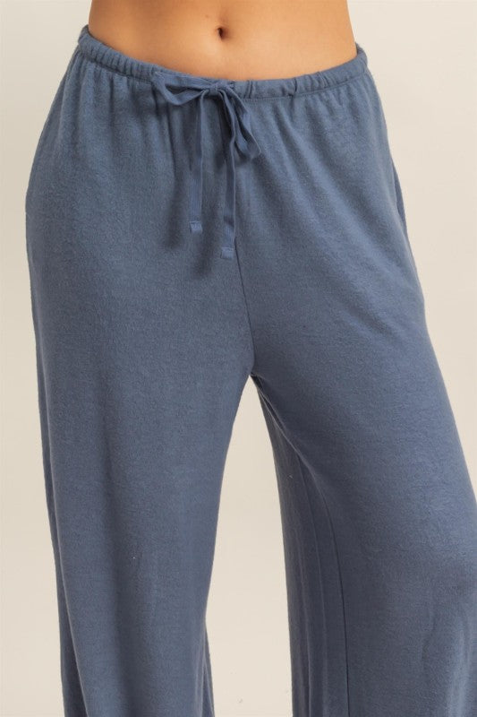 Blue pajama pants with a drawstring on a light beige background