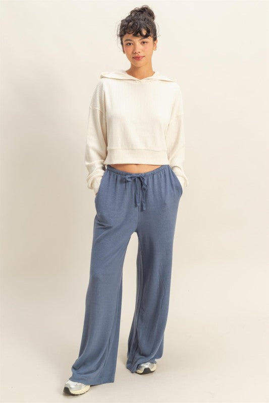 Person wearing a white sweatshirt and blue pants on a plain background