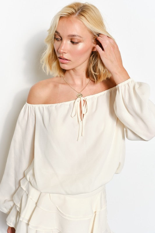 Woman wearing a white off-shoulder top with a plain background