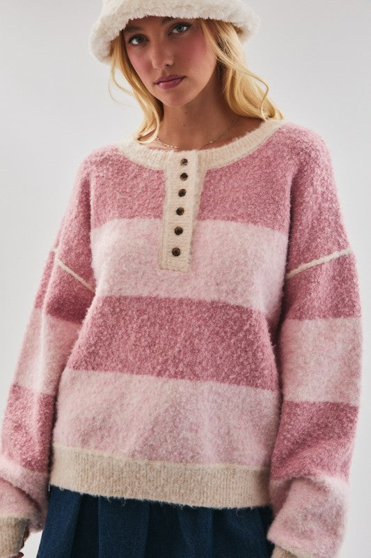Woman wearing a pink and white striped sweater with a plain background