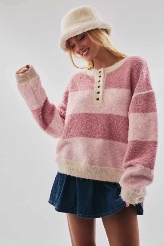 Woman wearing a pink and beige striped sweater with a white background