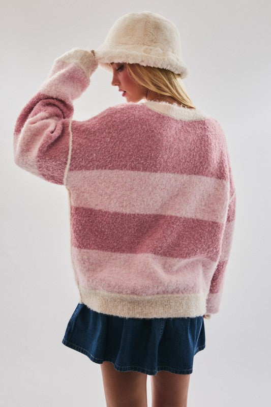 Person wearing a pink and white striped sweater with a navy skirt and cream hat on a light gray background
