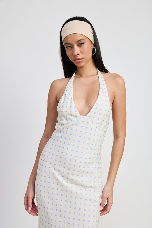 Woman wearing a white halter neck dress with a subtle pattern on a plain background