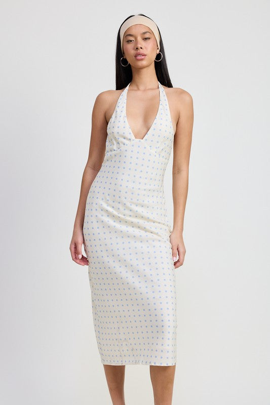Woman wearing a white halter neck dress with a subtle pattern on a plain background